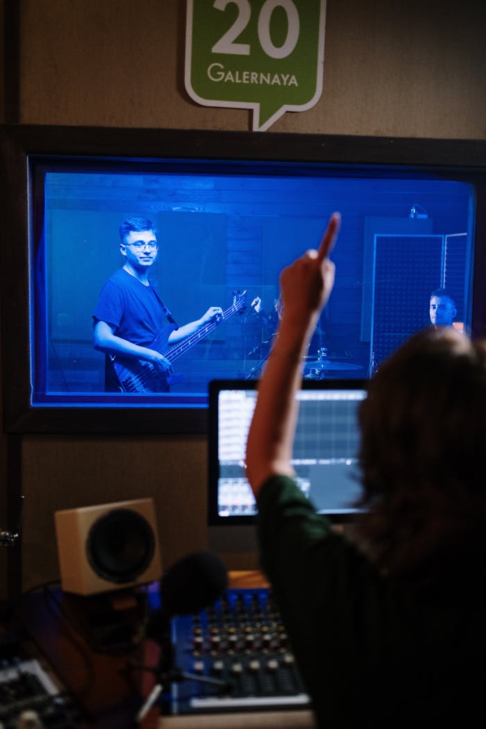 Musician playing guitar in a soundproof studio with sound engineer directing.